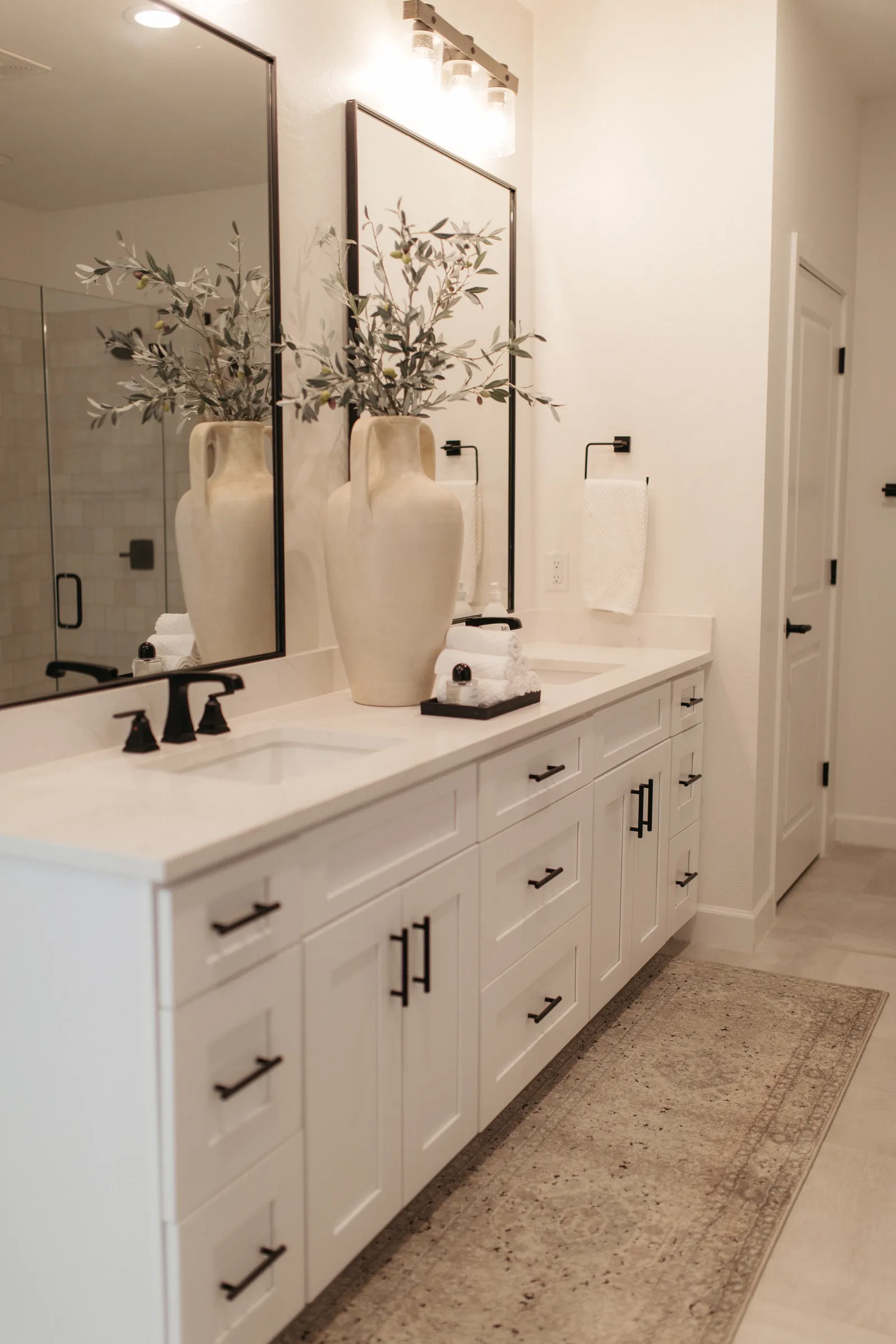 Double vanity with black fixtures and olive branches